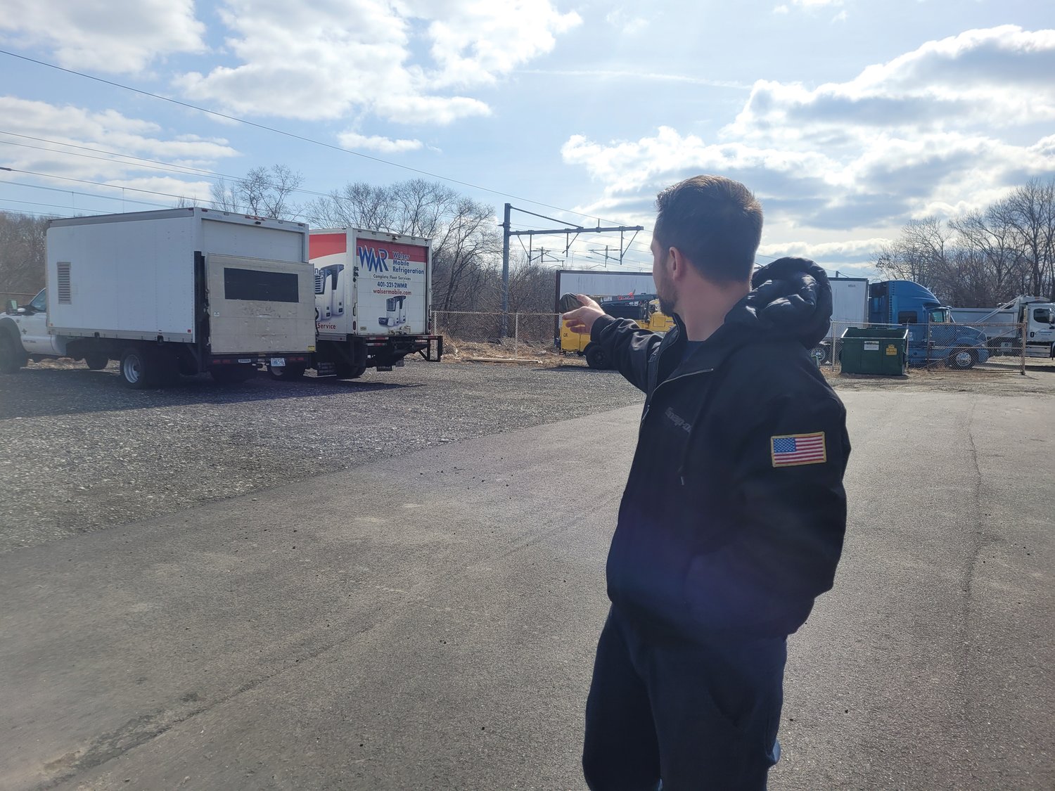 DAMAGED TRUCKS: Daniel S. Walser III points out two of the trucks damaged by a thief who stole the catalytic converters and sold them for cash at a metal recycling facility in Providence. Last week, the FBI and local police departments raided the Branch Avenue business, Accurate Converter.